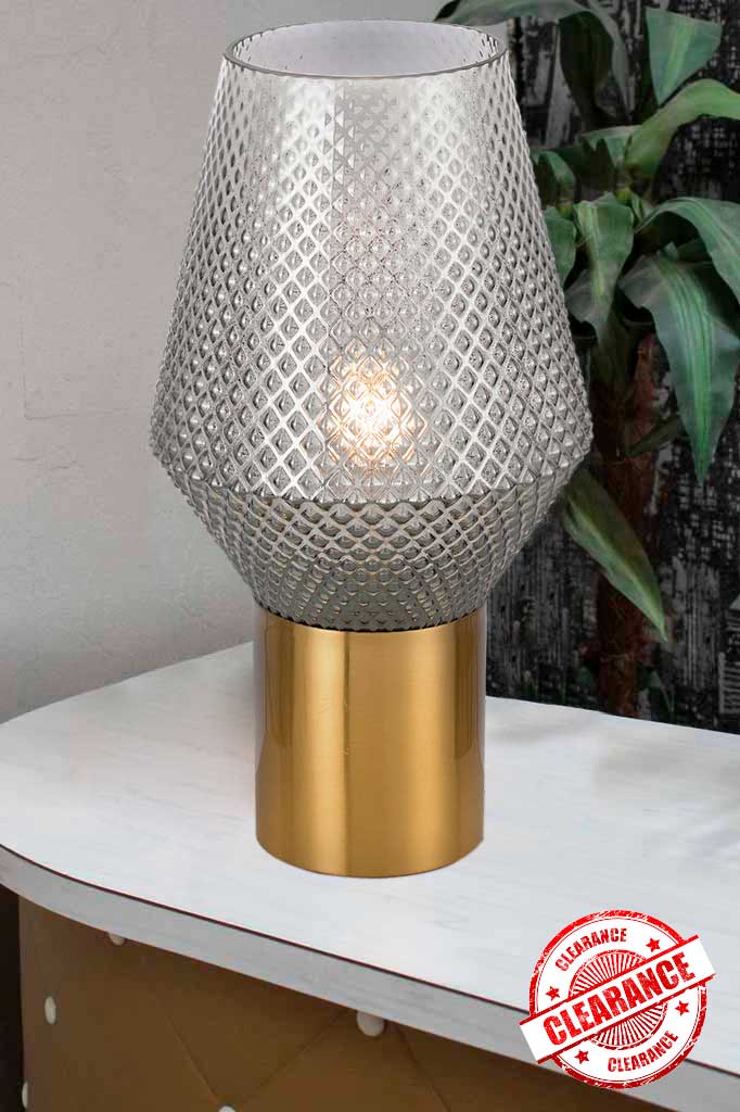 Grey smoke glass table lamp with antique gold base on a white table