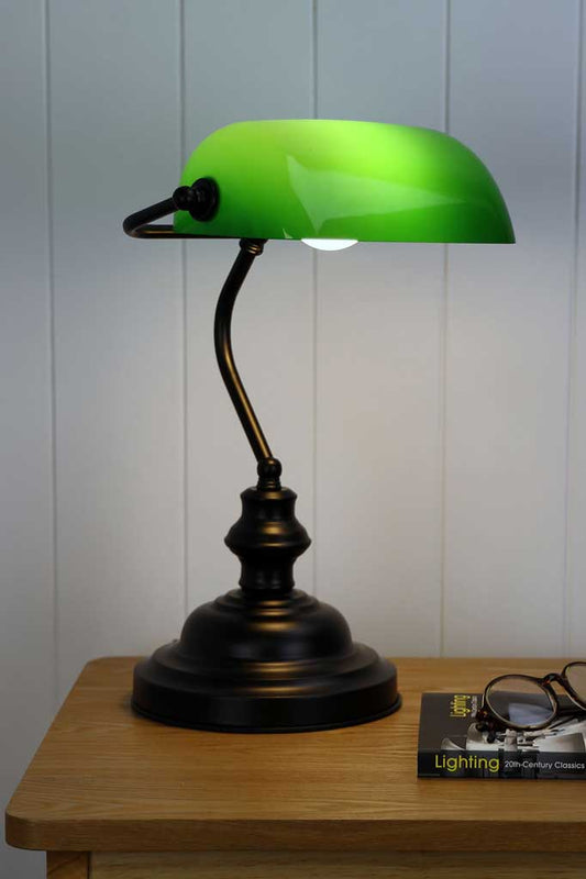 Bankers lamp with back stand and green shade on a side table. 