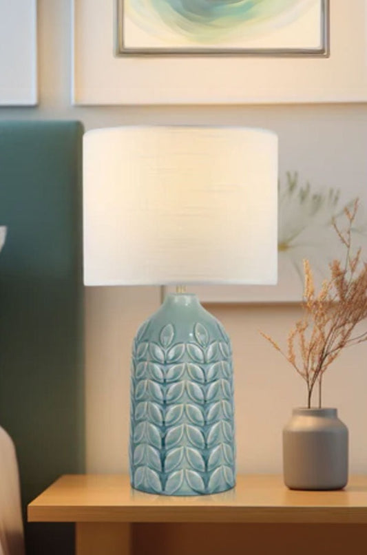 Blue ceramic table lamp complemented with a white linen drum shade.