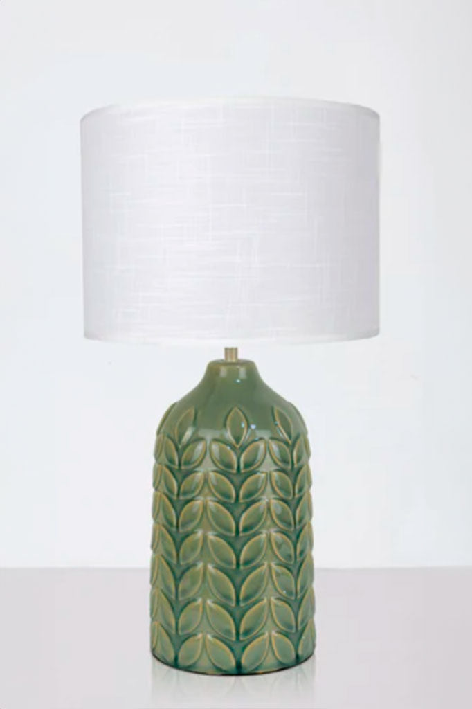 Green ceramic table lamp complemented with a white linen drum shade.