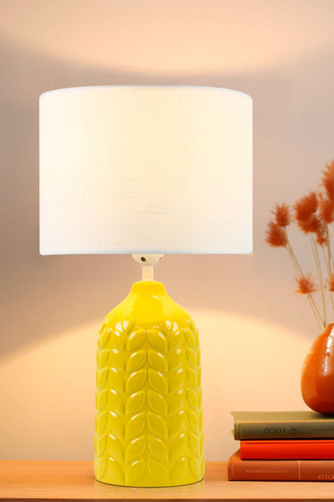 Yellow ceramic table lamp complemented with a white linen drum shade.