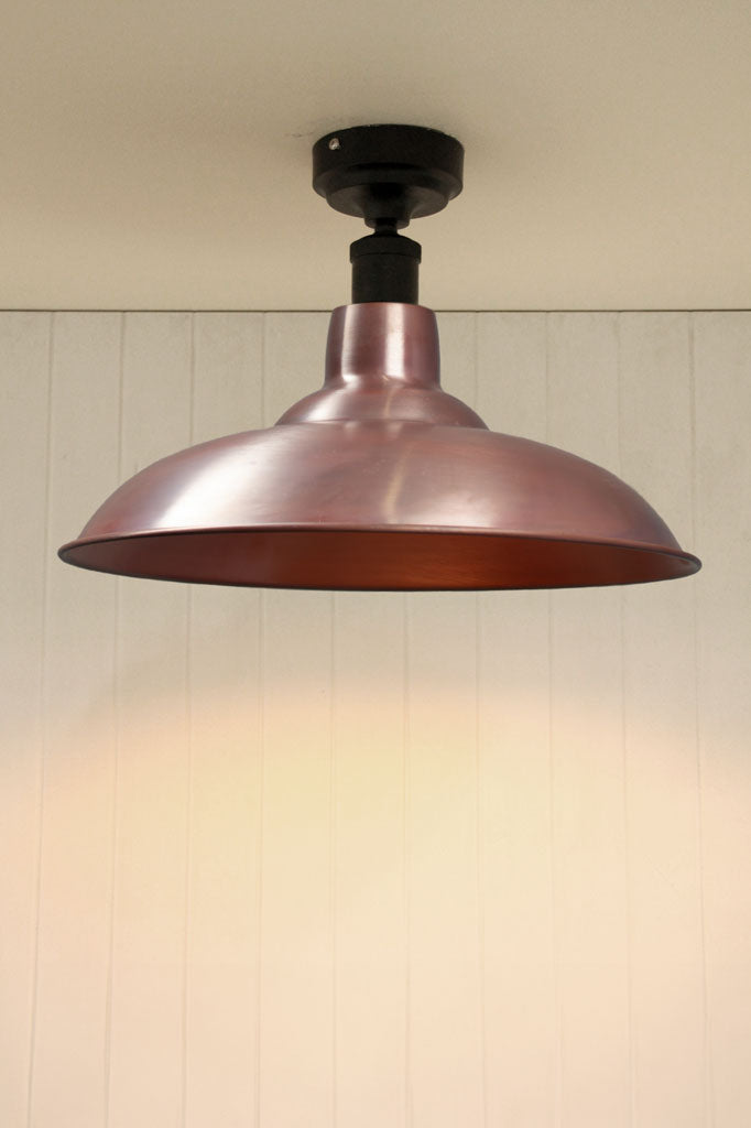 Aged solid copper barn shade on a black flush mount fixture. 