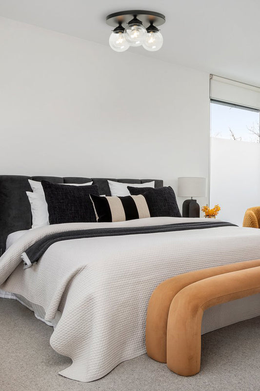 Thre clear glass ball shades on a black round ceiling mount in a bedroom. 