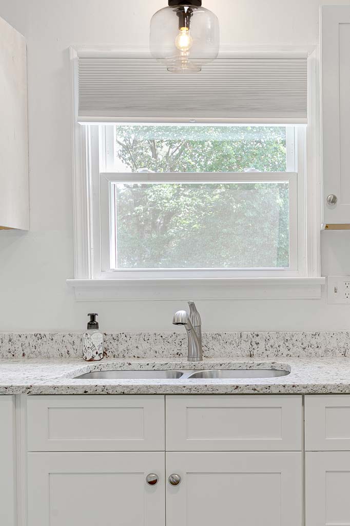 Clear glass open shade with black batenholder installed in a white kitchen. 