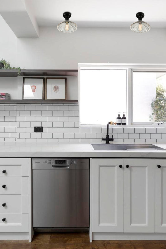 Two glass Paris pleated clear shades with black batten holders above a black and white kitchen