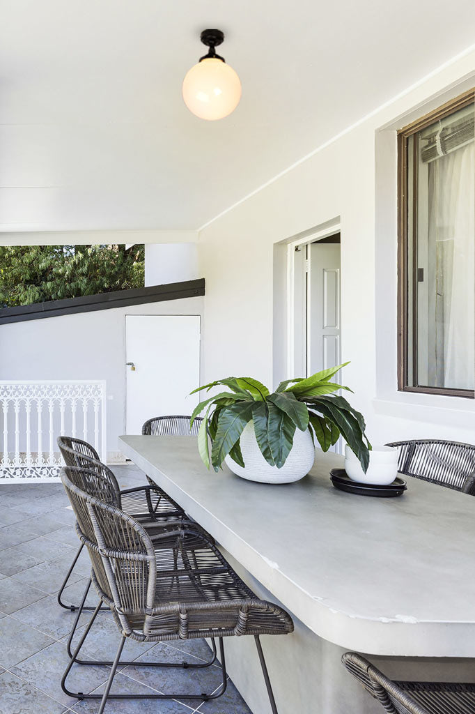 Outdoor opal glass ball ceiling light haning over an ourdoor dining space