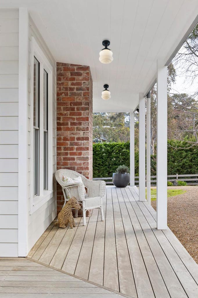 Two schoolhouse style opal shades on on flush mount fixtures installed under a verandah. 