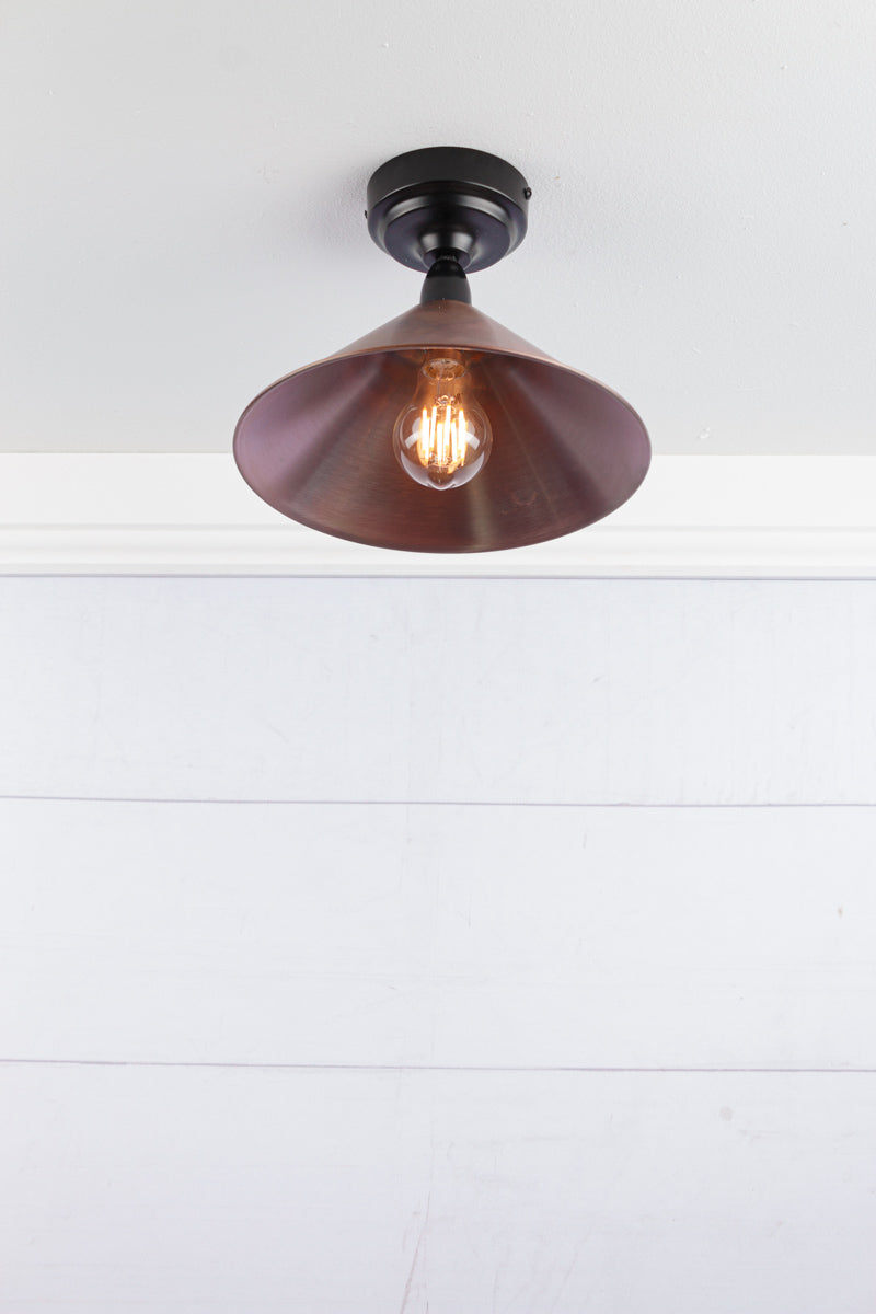 Small aged brass cone shade on a black IP rated battenholder.