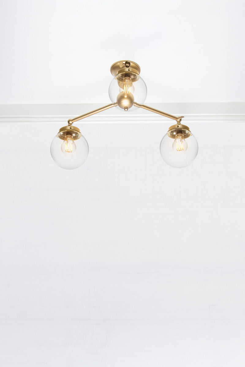 Small clear glass ball ceiling light with triple gold/brass straight arm fixture. 