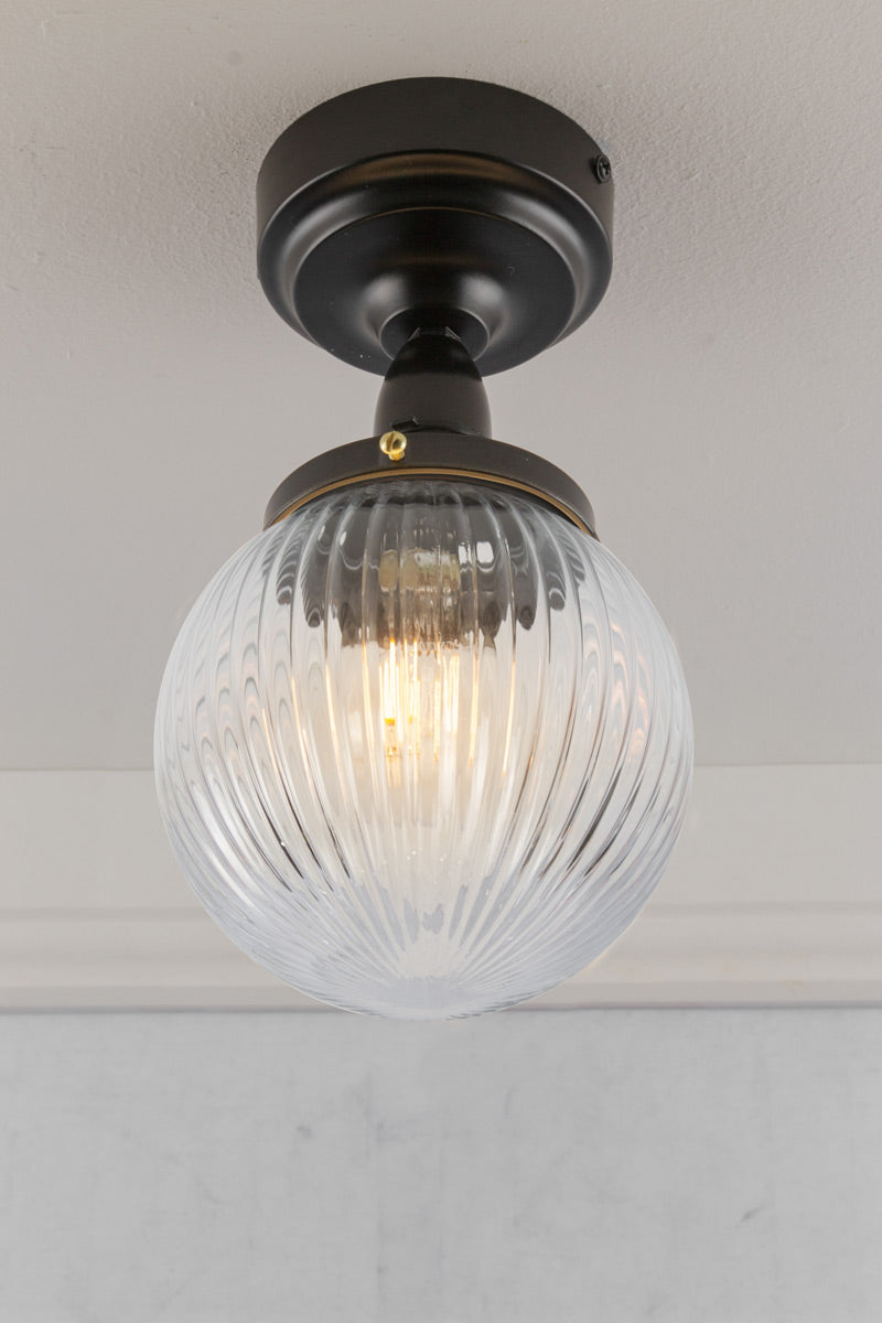 Clear reeded glass ball shade on an IP rated flushmount, under view.
