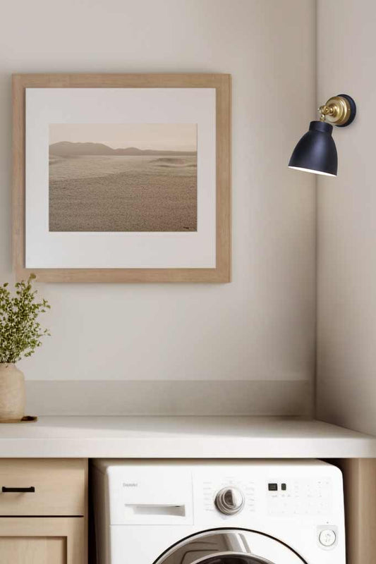 Black shade on a gold batten holder mounted on the wall of cream tone laundry. 