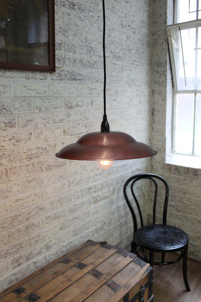 Copper barn shade pendant above vintage furniture