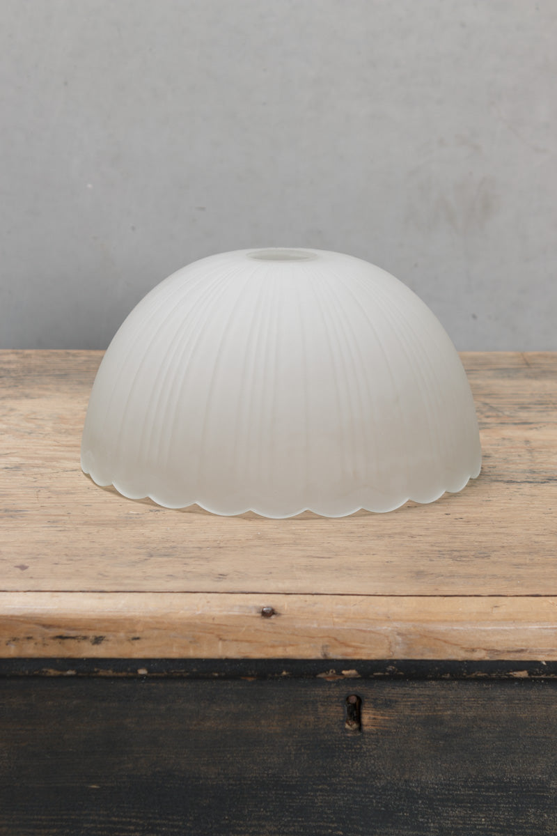 A weighty dome shaped shade has textured ridge detailing and a frost finish, with a distinctive scalloped edging for added flair.