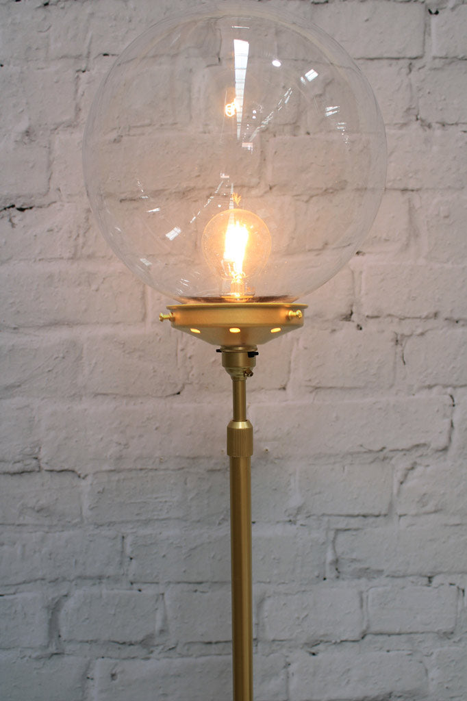 Close up of the medium clear glass ball shade on a gold/brass lamp stand