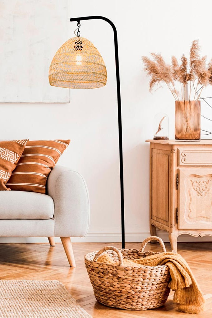 Black floor lamp with suspended rattan shade in a living room 