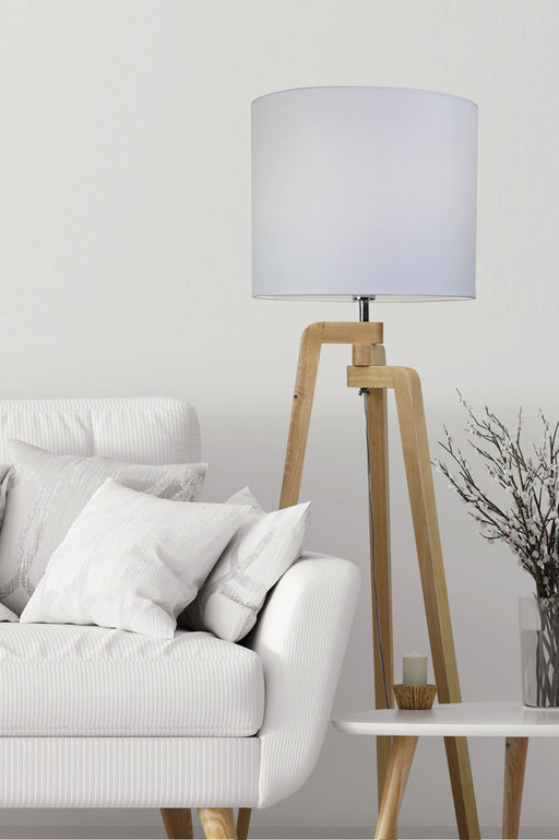 Wooden Tripod Floor Lamp next to a white couch and coffee table. 