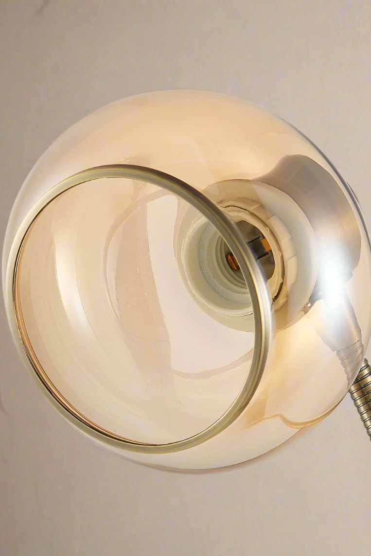 Close up of the front of a Antique brass floor lamp with an amber glass shade