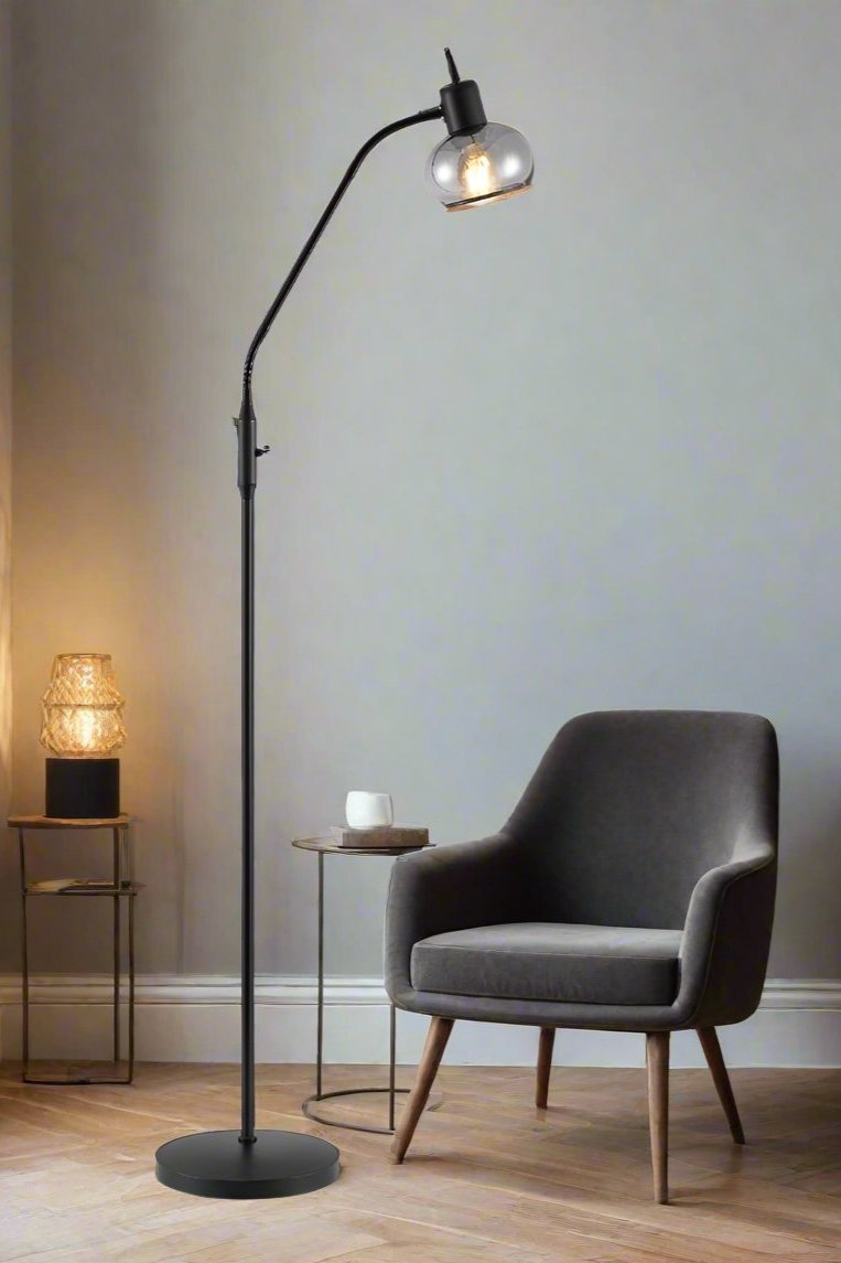 Black floor lamp with smoked glass shade in a reading nook