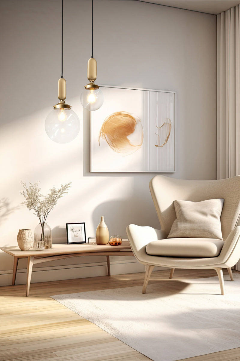 Medium and large clear glass balls with gold tubes on black pendants in a lounge room. 