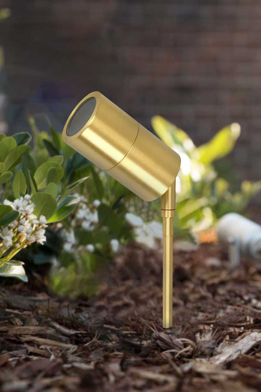 Delany Garden Spike Spot Light in polished brass installed in soft landscape. 