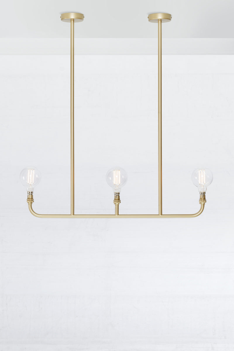 Triple lamp linear chandelier in gold/brass. 