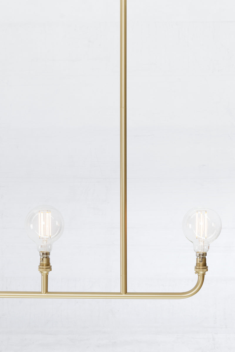 Close up of the triple lamp linear chandelier in gold/brass. 