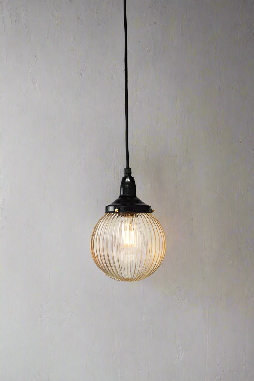 Amber reeded glass ball shade on a black IP rated pendant cord.