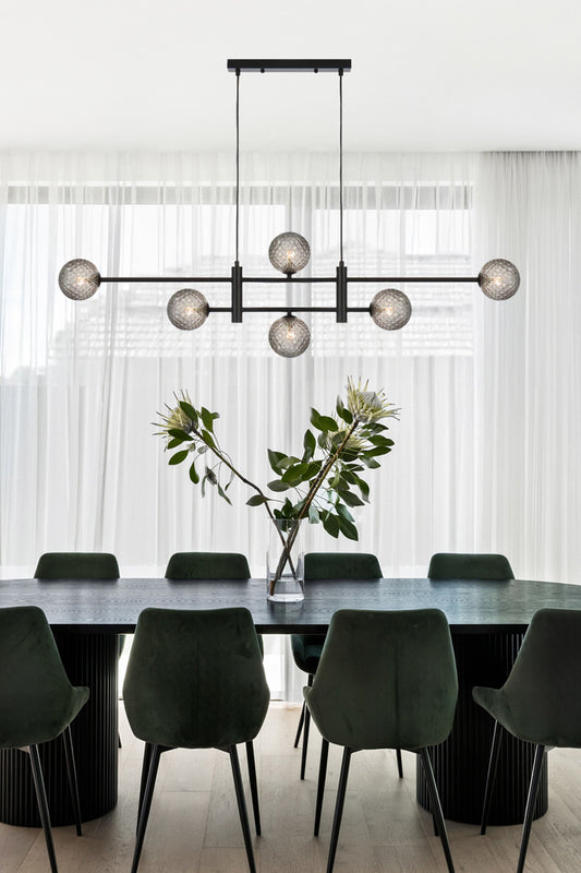 Black 6 light linear chandelier with glass ball shades in a clearsmoke tear, hanging above a dining space.  