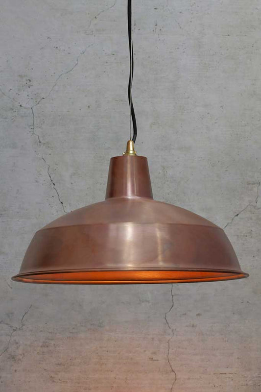 Small copper shade on a steel cable with gold lampholder and black cord. 