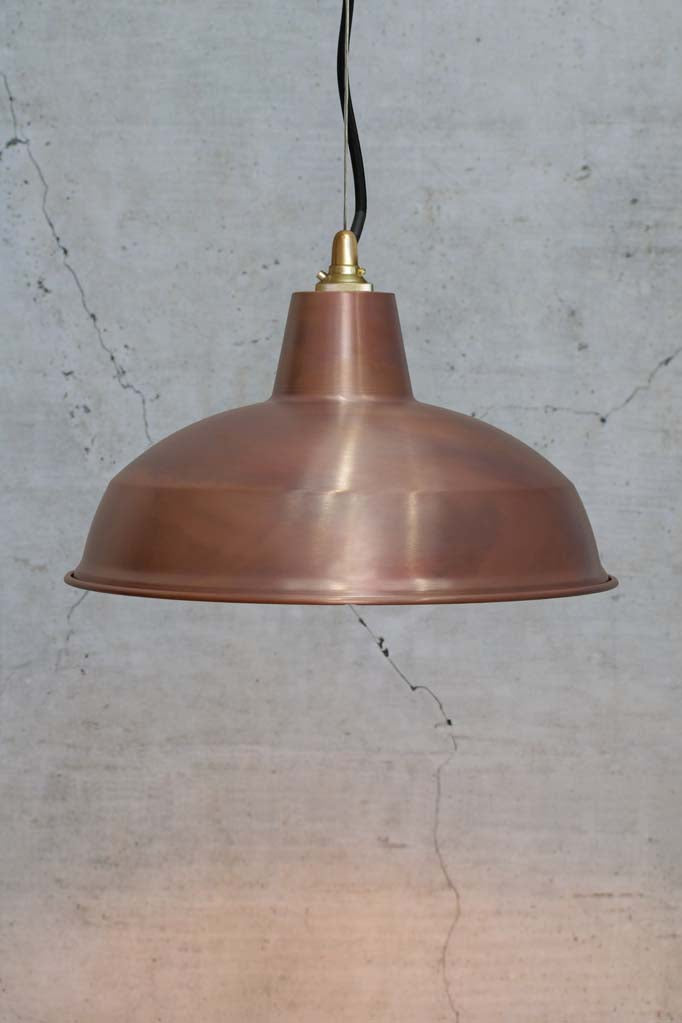 Large copper shade on a steel cable with gold lampholder and black cord. 