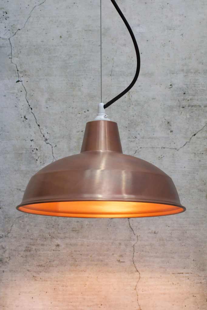 Small copper shade on a steel cable with white lampholder  and black cord. 