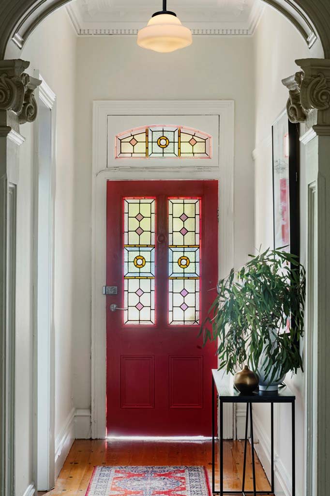 Schoolhouse Shade Pendant Light - Yarra, hanging in a bright entryway with a red door. 