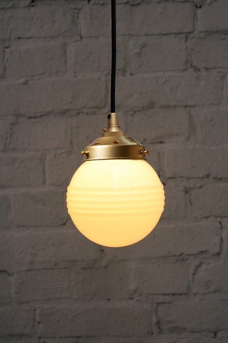 Pendant light with ridged opal glass shade and gold/brass round cord