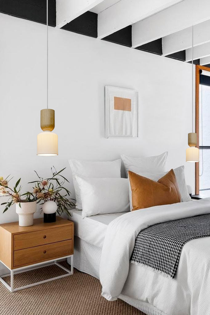 Three ceramic pendant lights with wooden blocks hanging over bedsides