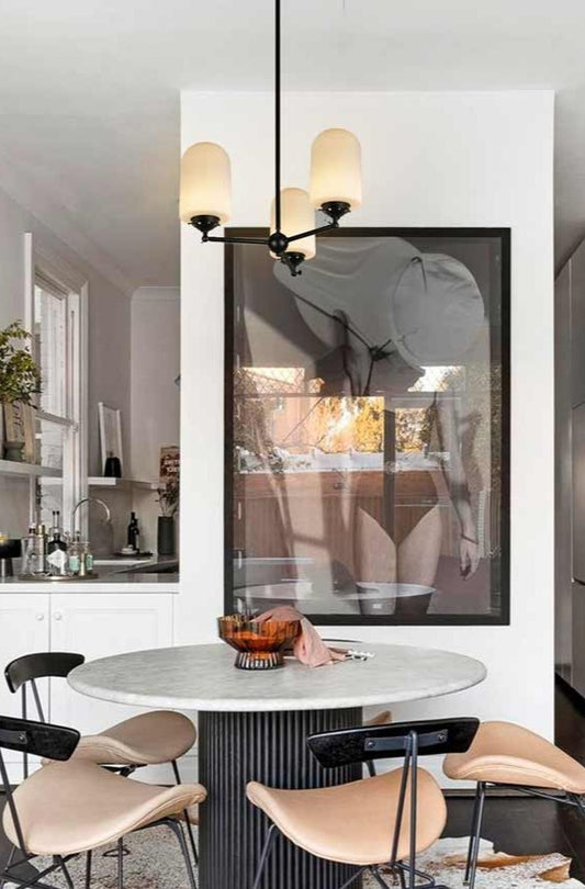 Lloyd Reeded Glass Chandelier with opal shades and black fixture hanging over dining table.