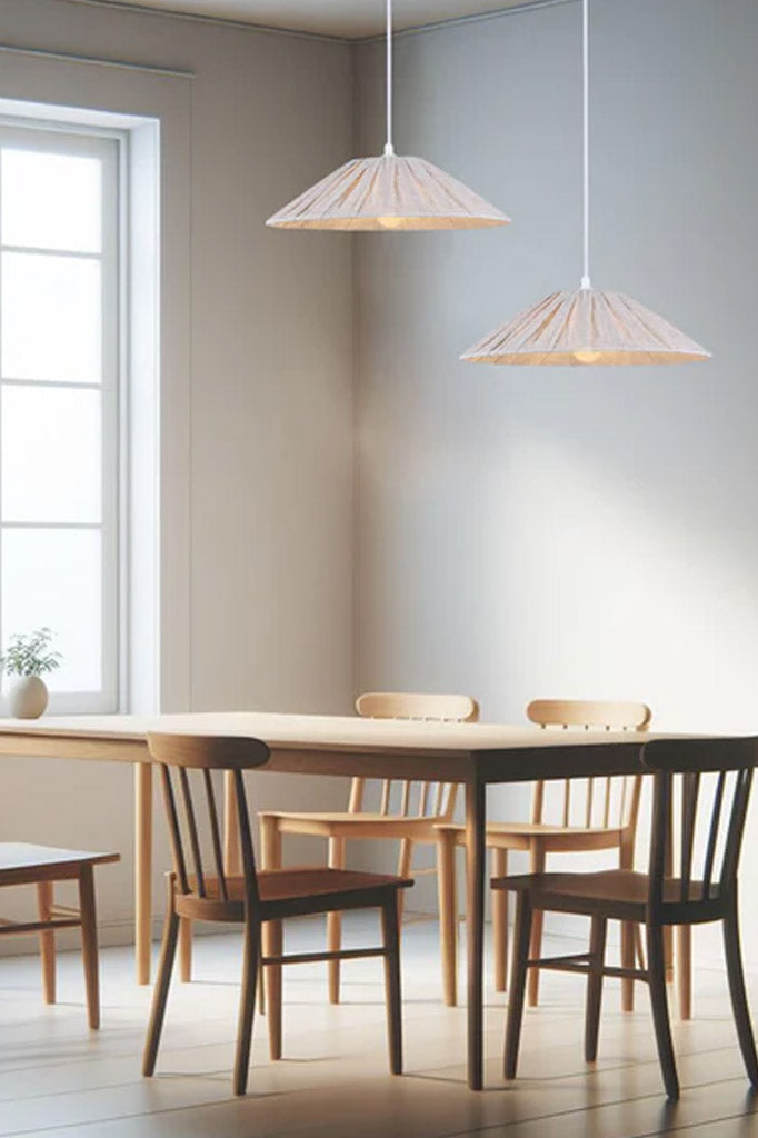 Two small linen pendant shades hanging over a dining space. 