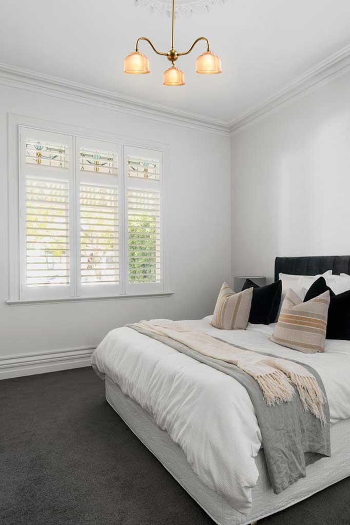 3 Arm gold/brass gooseneck chandelier with holophane shades in a bedroom. 