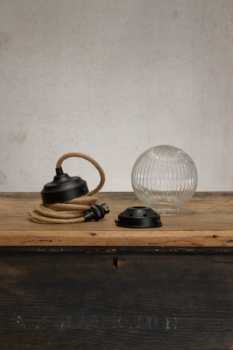 Deconstructed Clear reeded glass ball shade on a jute pendent cord with black metalware. 