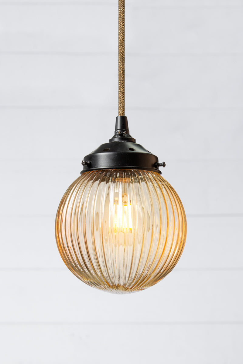 Amber reeded glass ball shade on a jute pendent cord with black metalware. 