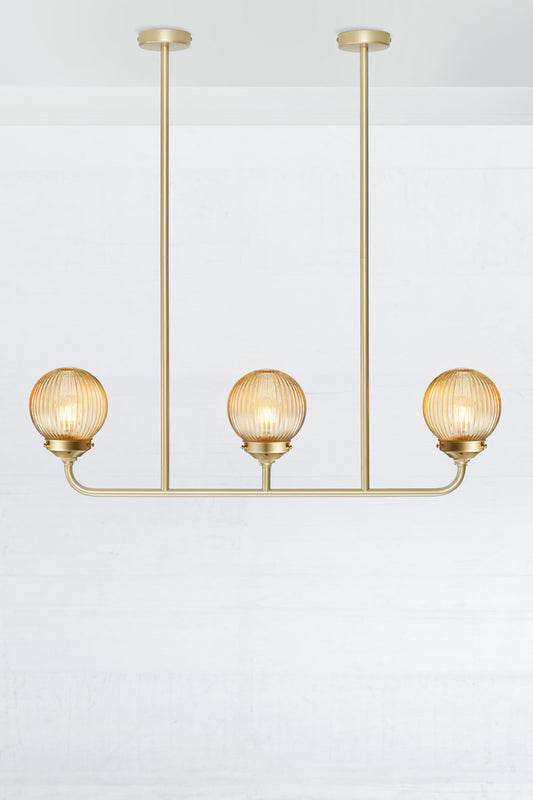 Gold/Brass triple lamp linear chandelier with amber reeded glass ball shades. 