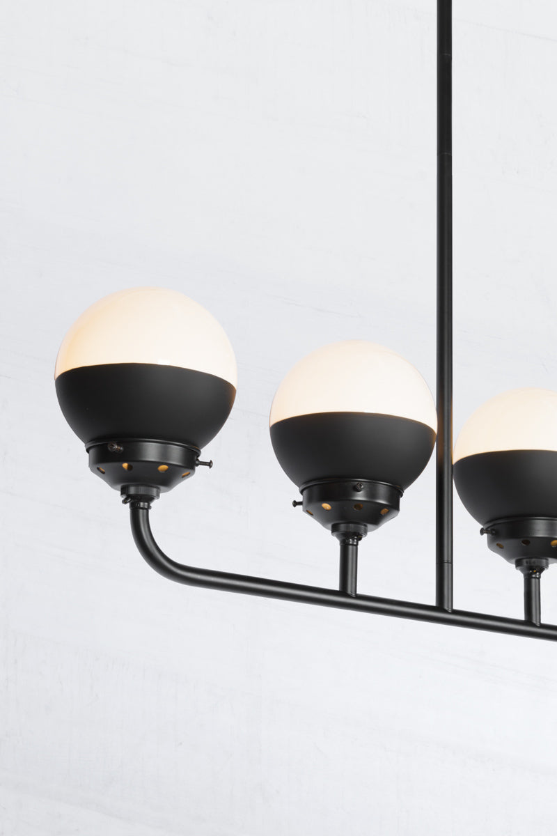 Close up of the Crown sphear shades on a five lamp linear black chandelier. 