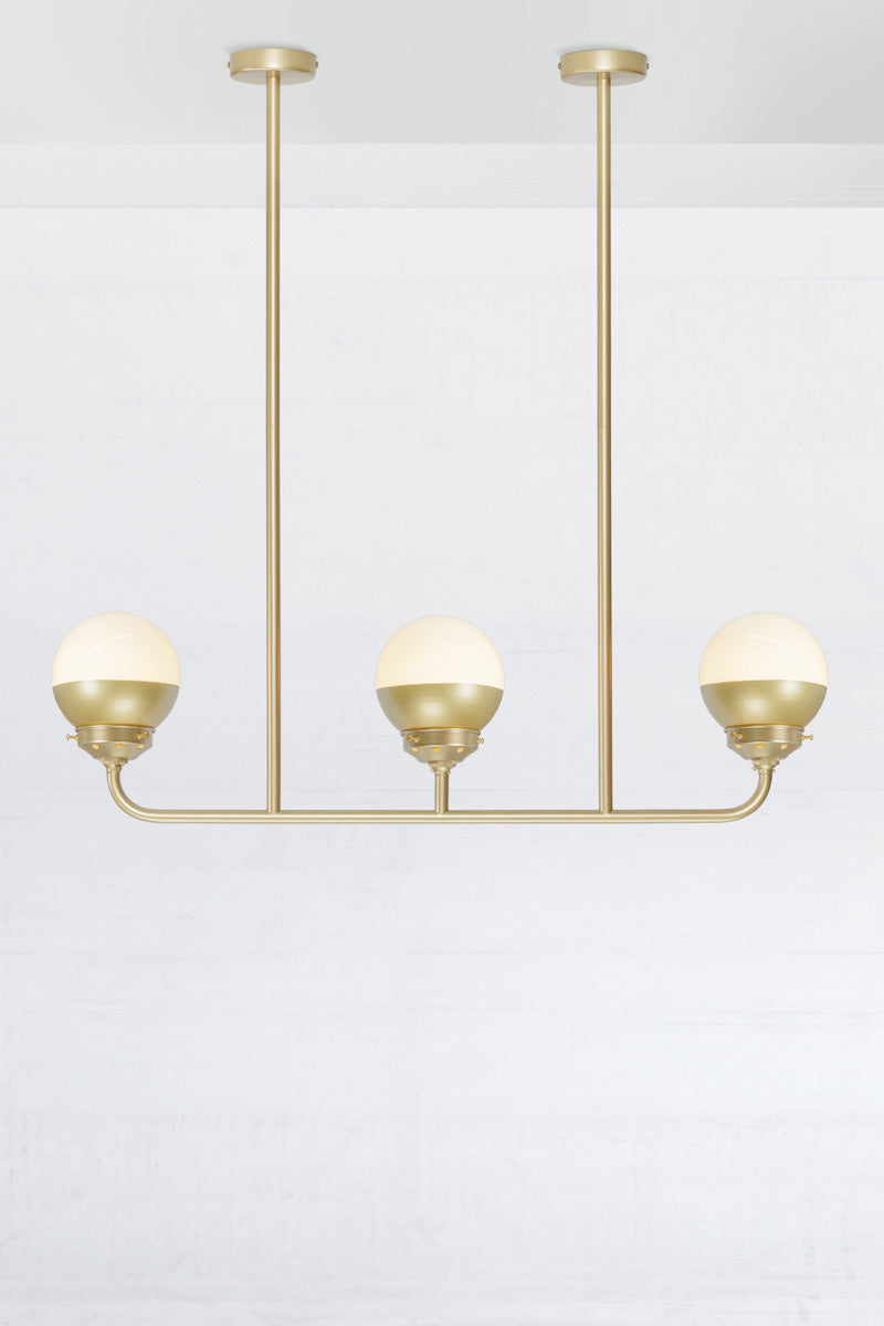 Crown sphear shades on a triple lamp linear gold/brass chandelier. 