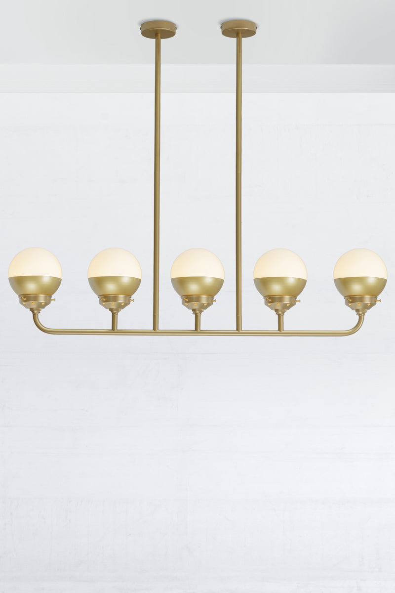 Crown sphear shades on a five lamp linear gold/brass chandelier. 