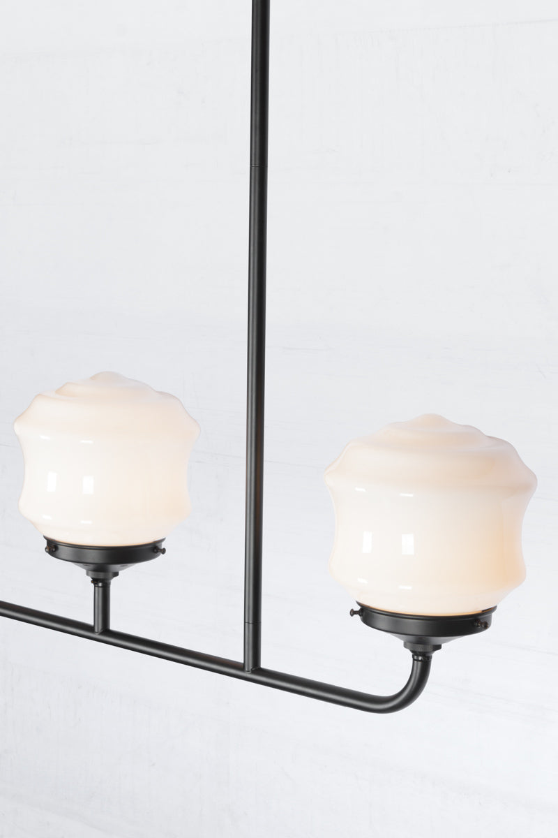 Close up of the triple lamp black linear chandelier with schoolhouse style flinders opal shades. 