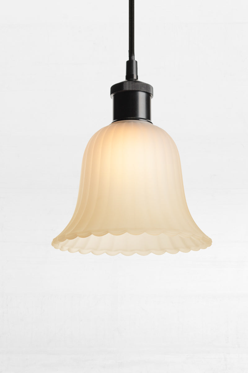 Featuring subtle ridges and scalloped edging, its bell shaped glass shade is enhanced with a frost finish