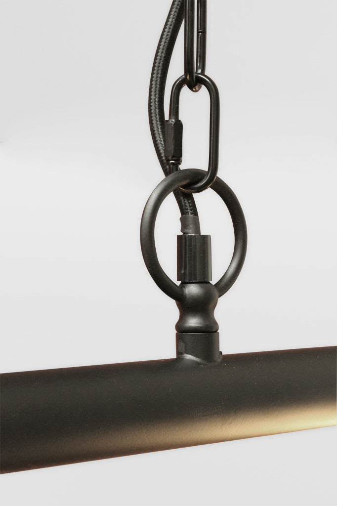 Close up o the chain/cord and bar joint of the black linear bar pendant fixture. 