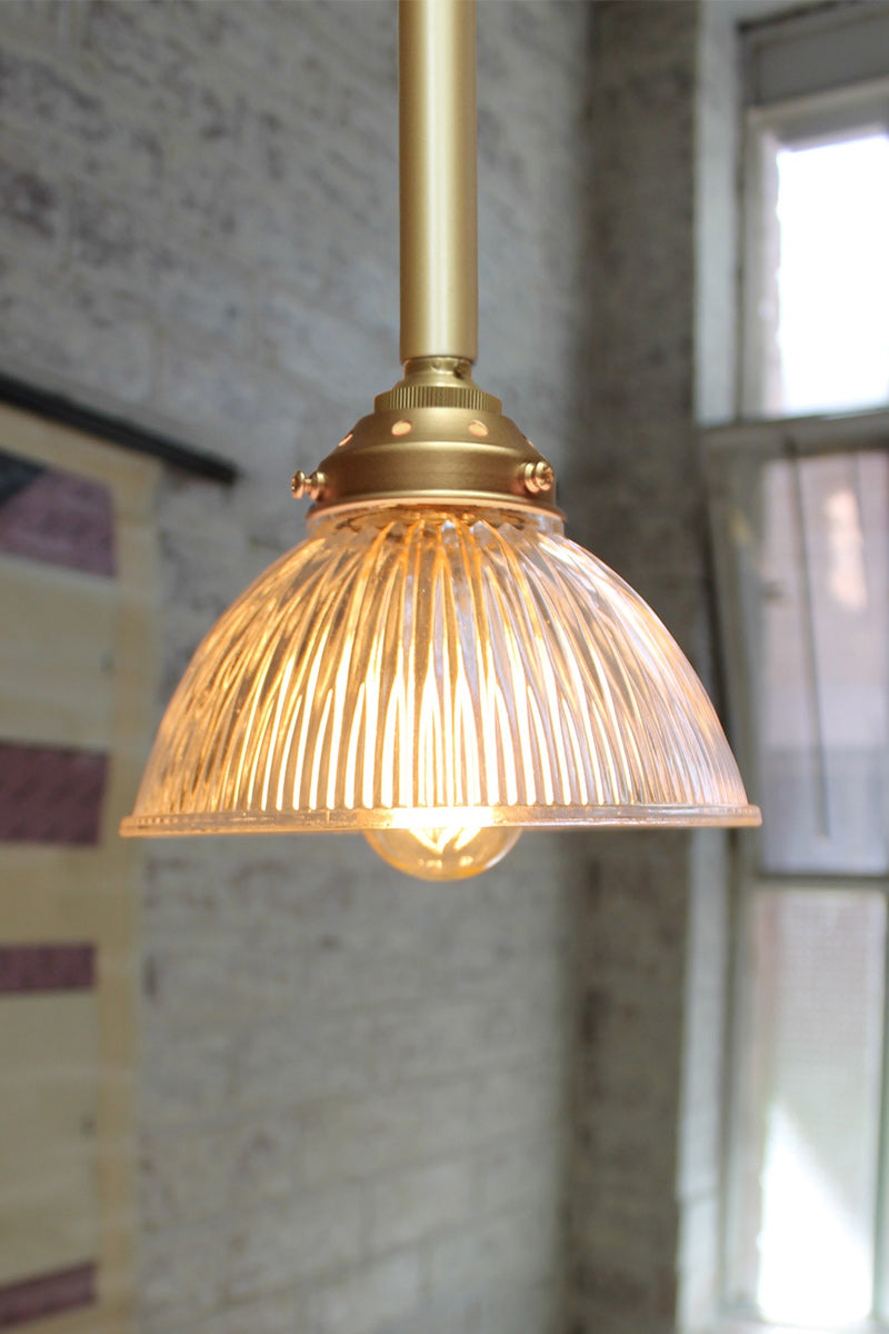 Gold/brass pole pendant with a clear glass ribbed shade. 