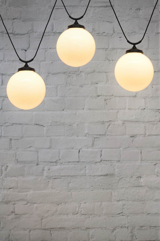 Three large round opal glass shade with trapeze pendant cords.