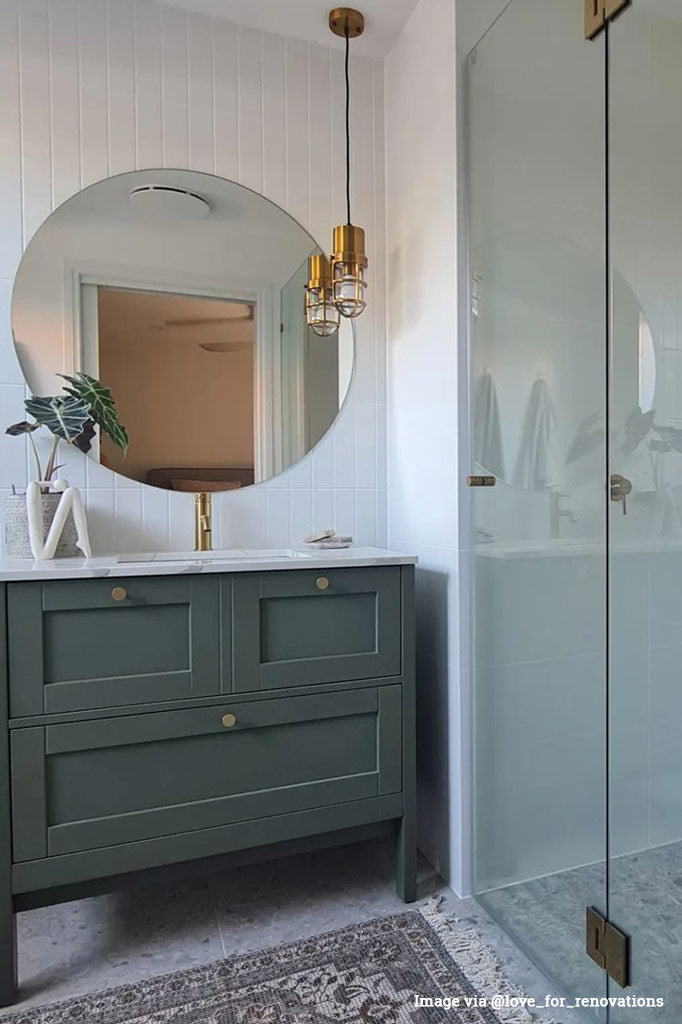 One brass caged Anchorage Bunker pendant light hanging in a bright bathroom on a black cord.