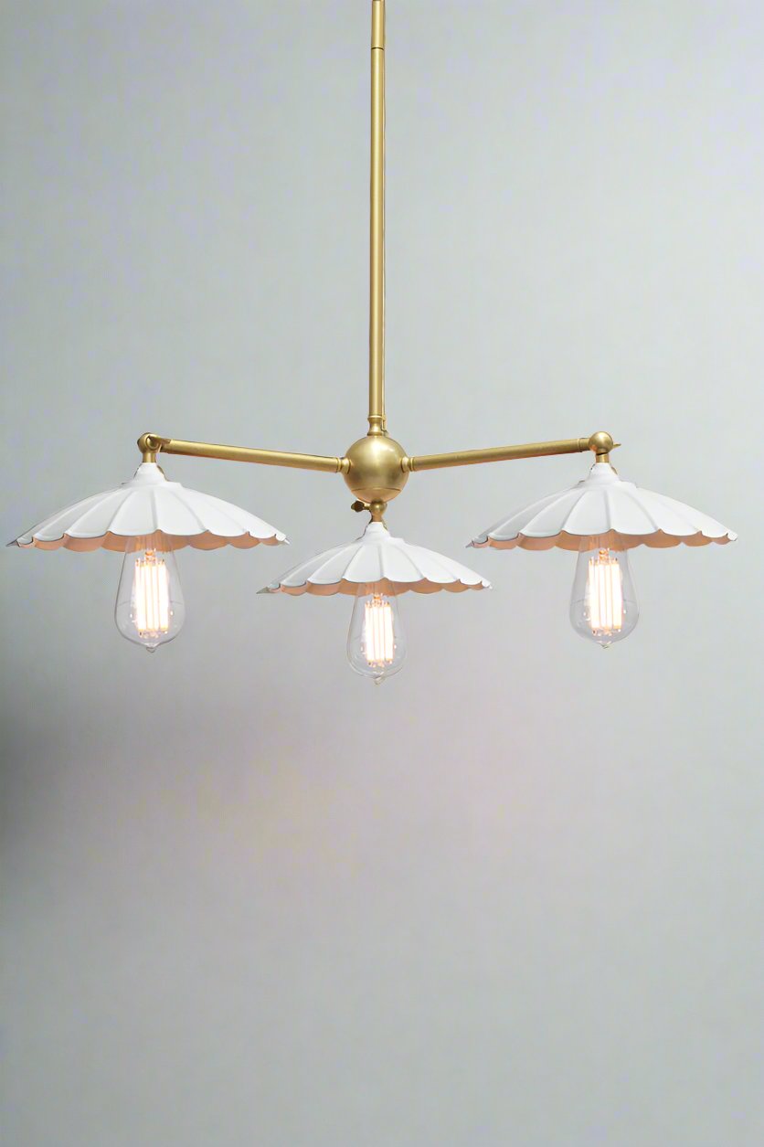 Gold/Brass 3 straight arm chandelier with white umbrella shades and teardrop bulbs. 